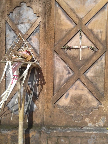 A bamboo cross is placed in a decorative wall with offerings next to it.  (Photo by Garrett Kam)