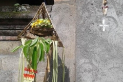 A bamboo cross with skewer of onion, garlic and chili along with altar of offerings outside a housegate. (Photo by Garrett Kam)